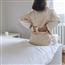 Woman sitting on edge with hands supporting lower back and stretching it out