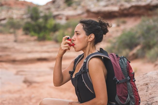 Person using inhaler while hiking Person using inhaler while hiking