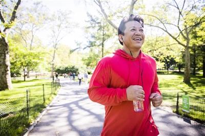 Man jogging outside, listening to something through earbuds and carrying a water bottle