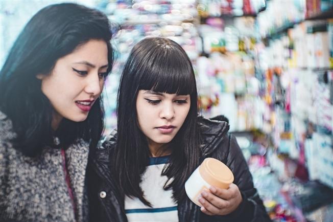 Two women looking at a beauty product's label at the store Two women looking at a beauty product's label at the store