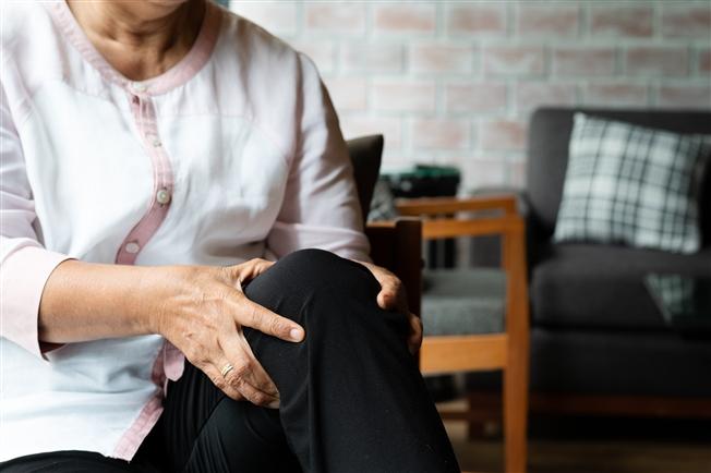 Woman clutching knee in pain Woman clutching knee in pain