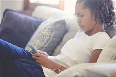 Young girl upset on couch scrolling through phone