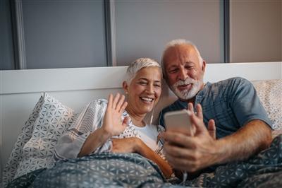 Older couple waving at phone on video chat with family