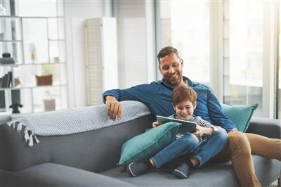 Father with son at home watching something on tablet