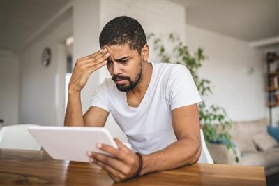 Worried man reading news on tablet
