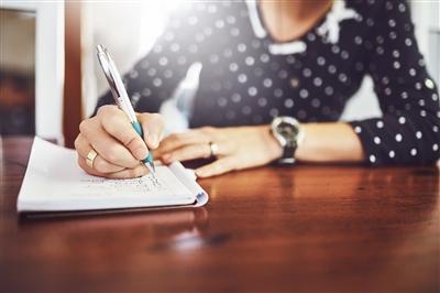 Close up of womans hand writing in notebook