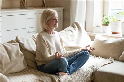 Mindful healthy mature woman practicing yoga meditation at home Mindful healthy mature woman practicing yoga meditation at home