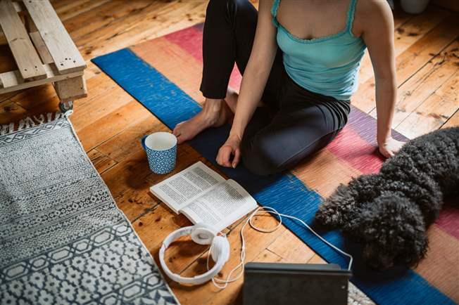 Woman on yoga mat surrounded by music pet and coffee Woman on yoga mat surrounded by music pet and coffee
