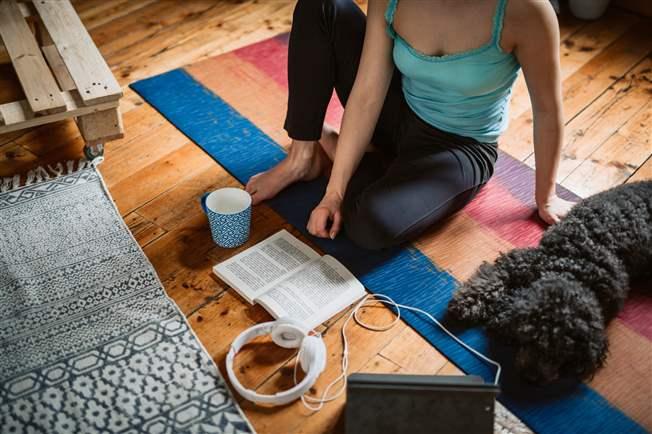 Woman on yoga mat surrounded by music pet and coffee