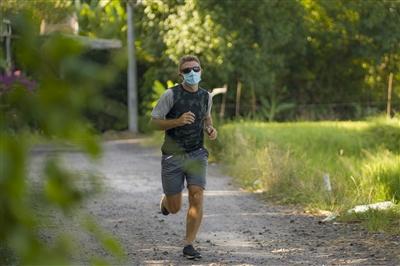 young attractive and happy man outdoors in city park doing running workout wearing protective face mask jogging and training young attractive and happy man outdoors in city park doing running workout wearing protective face mask jogging and training