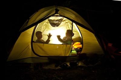 Two young children in tent in backyard at night playing games Two young children in tent in backyard at night playing games
