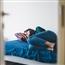Young adult woman laying on bed alone in room