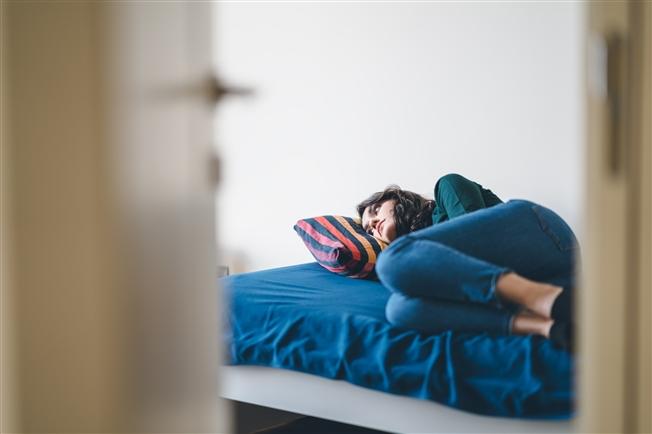 Young adult woman laying on bed alone in room Young adult woman laying on bed alone in room