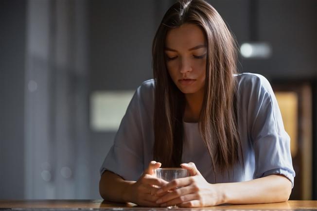 Young woman looking sad sitting alone at bar with glass of alcohol in her hand Young woman looking sad sitting alone at bar with glass of alcohol in her hand