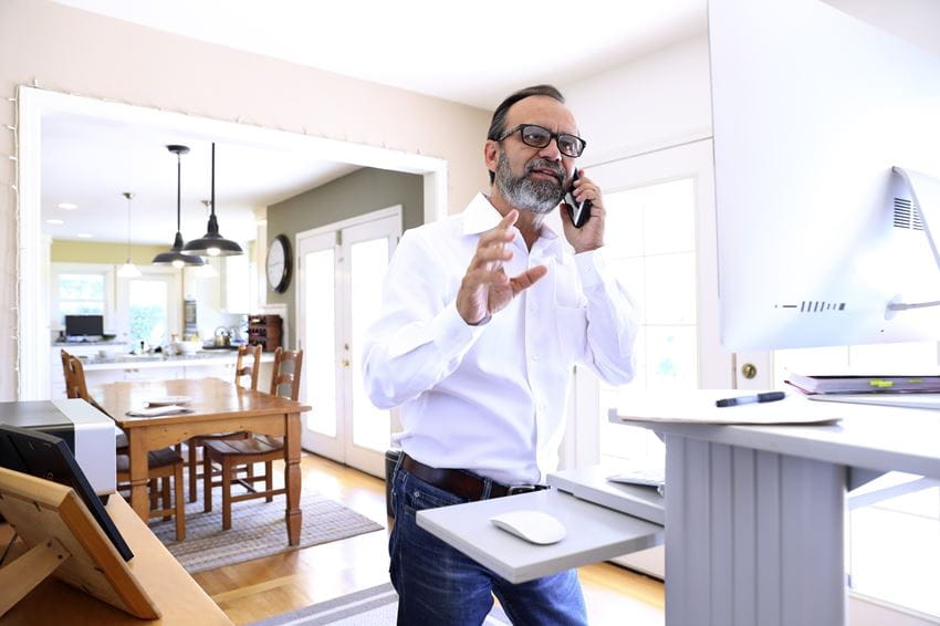 Businessman on the phone at home standing at standing desk