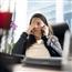 Woman sitting at desk showing physical symptoms of stress headache