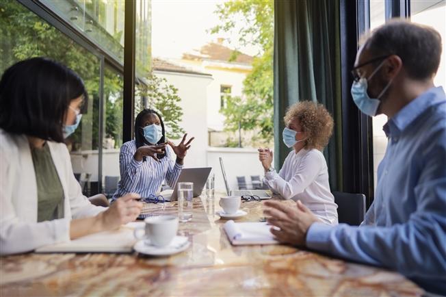 Diverse group of business people having a meeting at the coffee shop while wearing protective masks during coronavirus pandemic Diverse group of business people having a meeting at the coffee shop while wearing protective masks during coronavirus pandemic