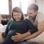 Man cradling pregnant wife's belly on couch