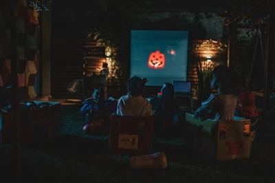 Kids watching Halloween movie on screen in backyard Kids watching Halloween movie on screen in backyard