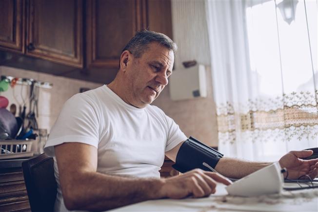 Middle aged man measuring high blood pressure at home
