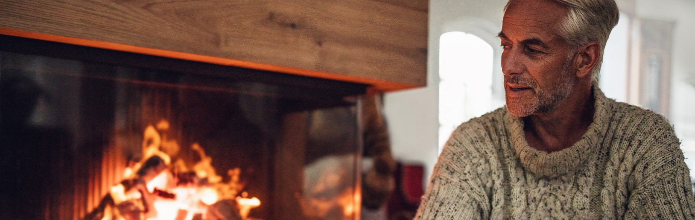 Mature man sitting by fire place in living room Mature man sitting by fire place in living room