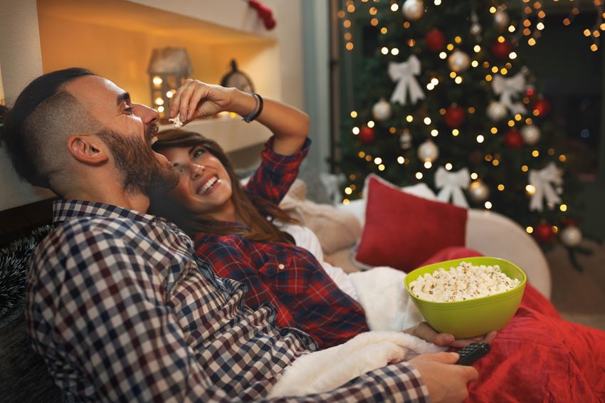 Young couple at Christmas enjoy with popcorn while watching tv