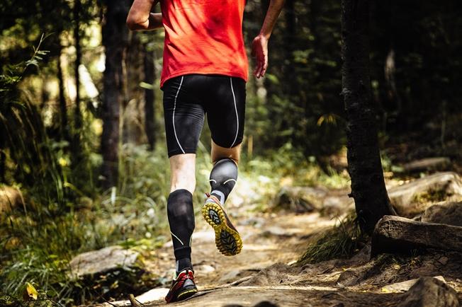 Runner in the forest wearing compression stockings on calves Runner in the forest wearing compression stockings on calves