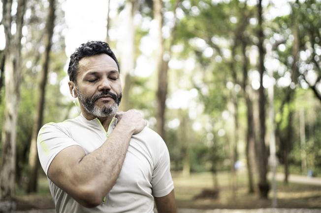 Middleaged man grasping shoulder in pain during workout Middleaged man grasping shoulder in pain during workout