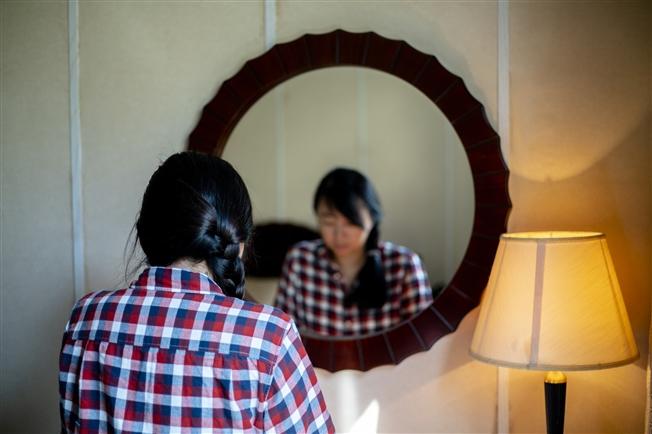 Adult woman looking down and sad in front of mirror Adult woman looking down and sad in front of mirror
