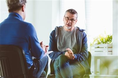 Middle aged man at appointment talking to therapist Middle aged man at appointment talking to therapist