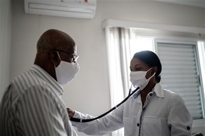 Female doctor checks heartbeat of a senior man