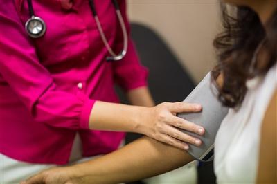Close up of female physician taking blood pressure of female patient