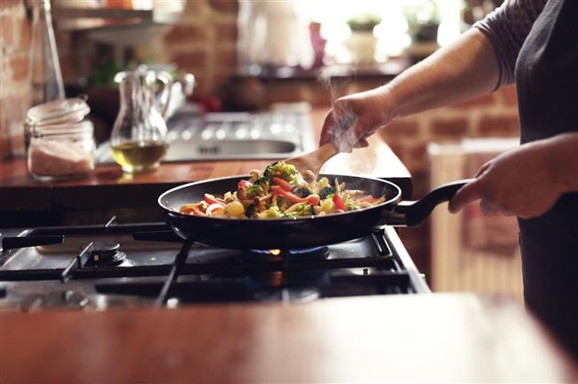 Woman cooking immune boosting foods like broccoli and peppers in stir fry
