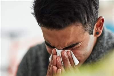 Young man blowing nose