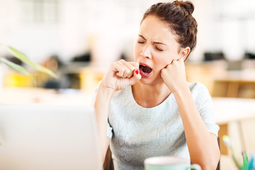 Woman at desk in home yawning