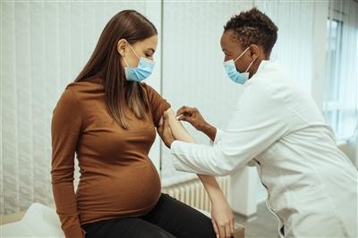 Doctor giving COVID vaccine to pregnant woman Young doctor giving COVID vaccine to pregnant woman in doctor's office