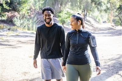 Young Black couple smiling and getting ready to go for a run on a trail