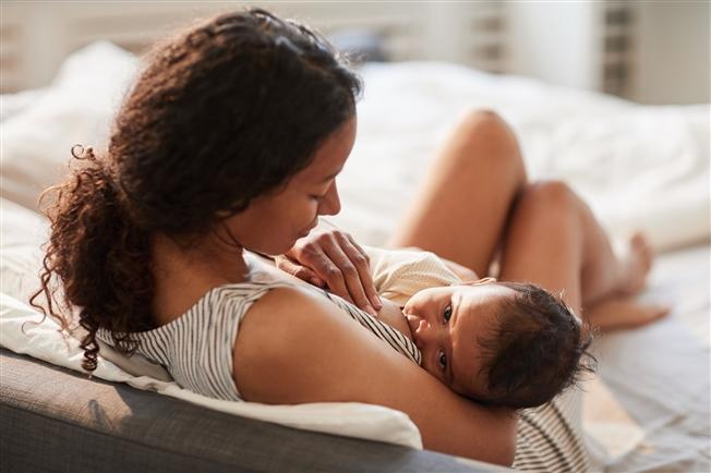 Young mother breastfeeding baby at home