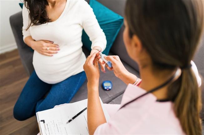 Doctor using a monitor to test the blood glucose of an expectant mother Gestational diabetes diagnosis and testing