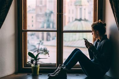 Young woman looking out window and feeling anxious