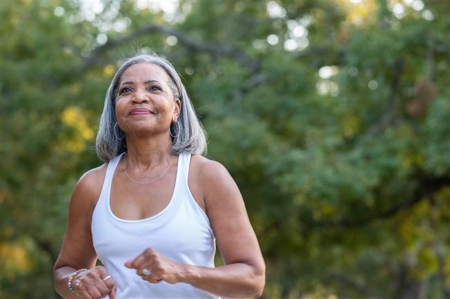 Senior woman jogging in park without headphones