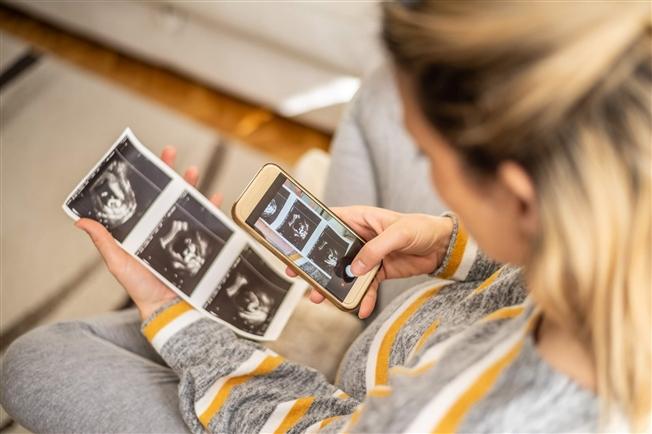 Pregnant woman taking photo of ultrasound with cell phone