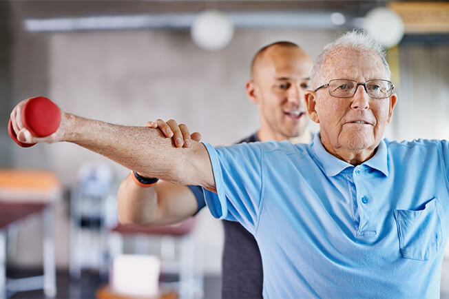 Older man strength training with therapist