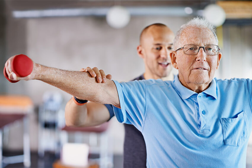 Older man strength training with therapist