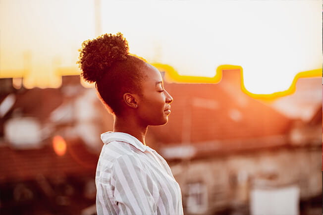 woman in sunshine, taking a deep breath