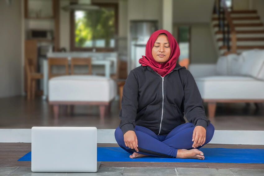 woman seated on floor in knees crossed position, meditating