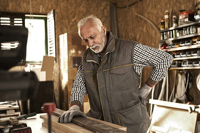 Older man in workshop with low back pain