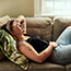Woman having stomach pain lying on sofa