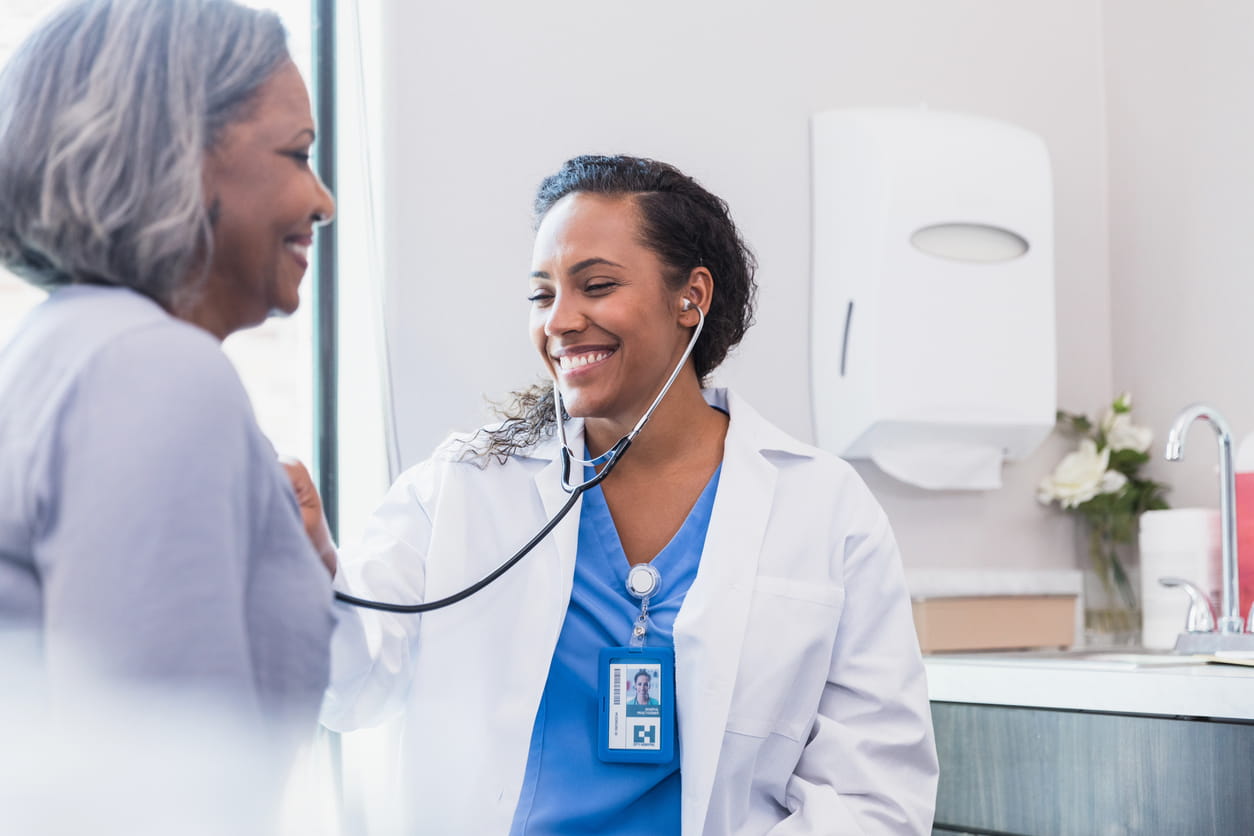 Smiling doctor listens to patient's heart