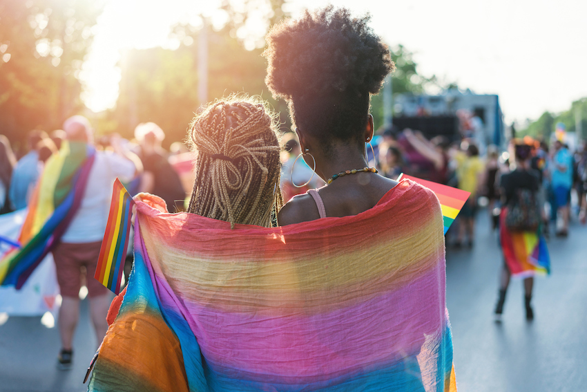 rainbow flag draped over young female couple